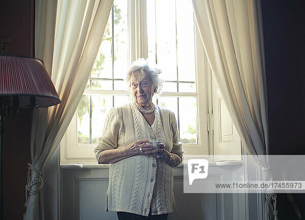 elderly lady drinks tea at home