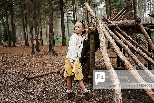 girl stood by wooden house in the forest in autumn