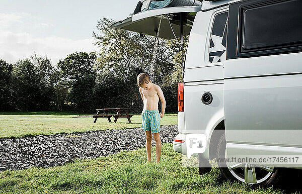 boy enjoying outdoor shower whilst camping in a camper van