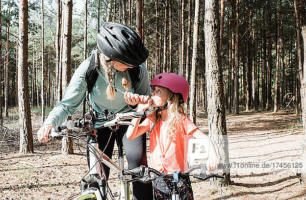 mother and daughter stopping to drink water whilst cycling together