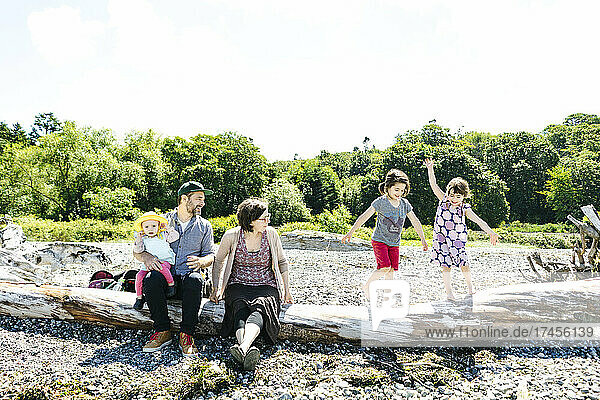 Straight on view of parents watching children balance on driftwood