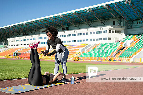 Multiethnic sportswomen doing abs exercise on stadium