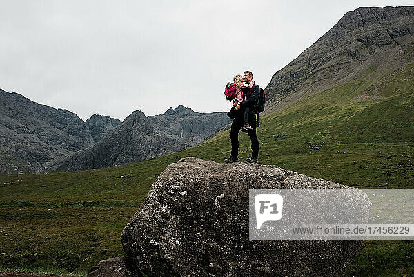 father hugging his daughter after climbing a giant boulder in Scotland