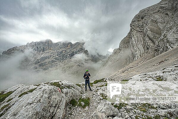 Wanderer  Bergsteiger auf einem Wanderweg zwischen felsigem wolkenverhangenen Gebirge am Forcella Sore de la Cengia  Sorapiss Umrundung  Dolomiten  Belluno  Italien  Europa