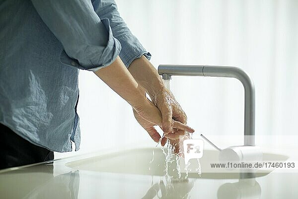 Japanese man washing hands in the kitchen