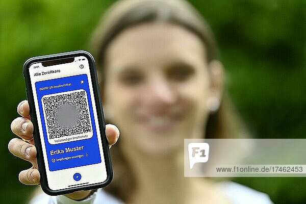 Symbol photo Vaccination privileges  young woman holding app CovPass on smartphone with digital European vaccination certificate including QR code  Corona crisis  Germany  Europe