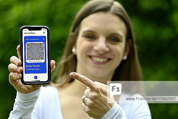 Symbofoto Impfprivilegien  junge Frau hält App CovPass auf Smartphone mit digitalem europäischen Impfzertifikat inklusive QR-Code  Corona-Krise  Deutschland  Europa