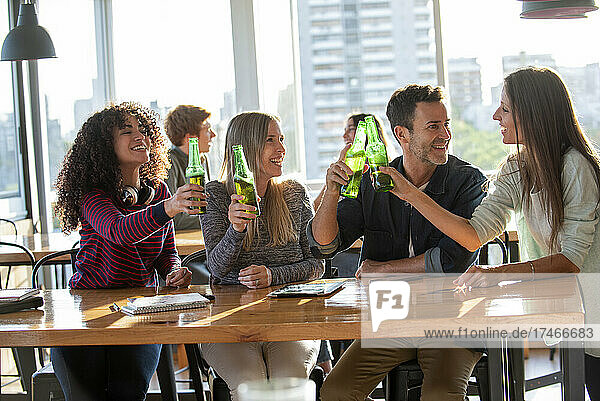 Smiling business people toasting bottles in office