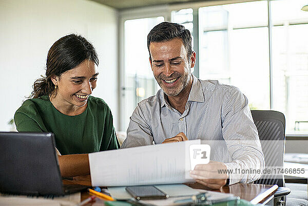 Smiling young woman and mature man working in office