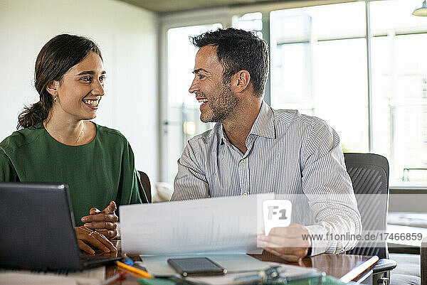 Smiling young woman and mature man working in office
