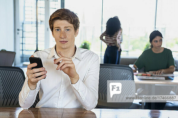 Portrait of young man using smart phone in office