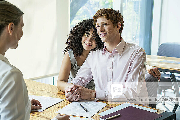 Young couple signing contract in office