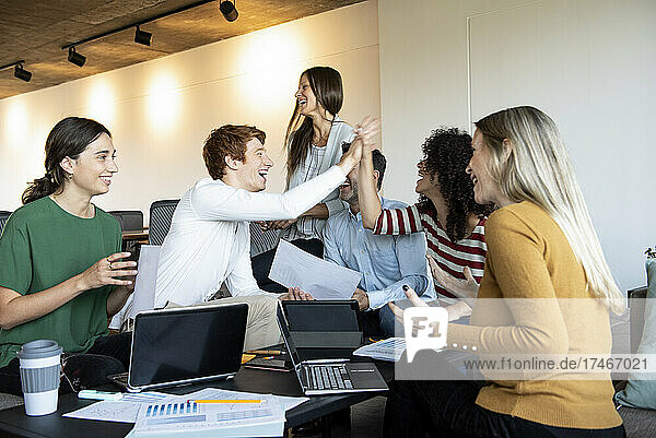 Colleagues giving high five at a group meeting
