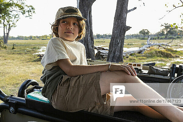 Ein Junge in einem Safarifahrzeug  der sich die Landschaft anschaut