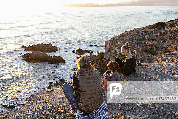 Eine Familie  Mutter und zwei Kinder  die den Sonnenuntergang über dem Meer beobachten.