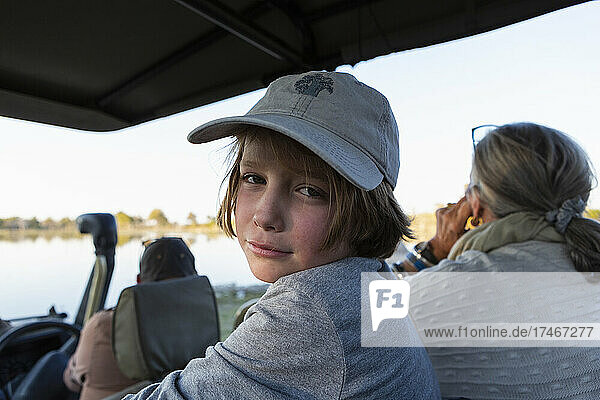 Junge in einem Safari-Jeep mit Baseballmütze schaut in die Kamera