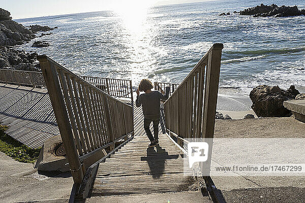 Ein Junge läuft eine Treppe hinunter zum Strand