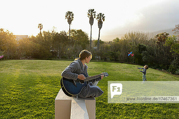 Teenage girl playing guitar and singing outdoors