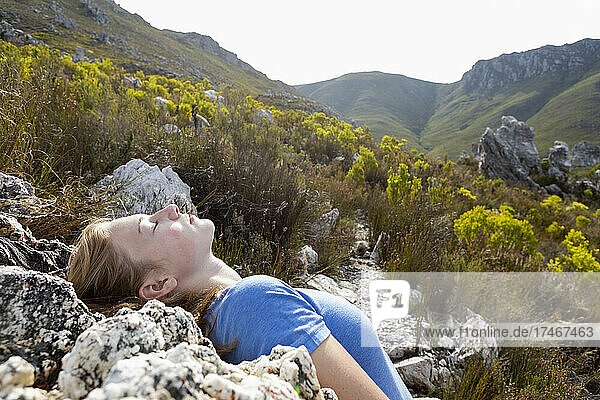 Teenager-Mädchen lehnt sich zurück und ruht sich auf einem Naturpfad in der Sonne aus