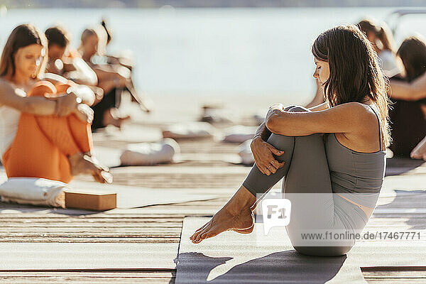 Female instructor hugging knees during yoga class