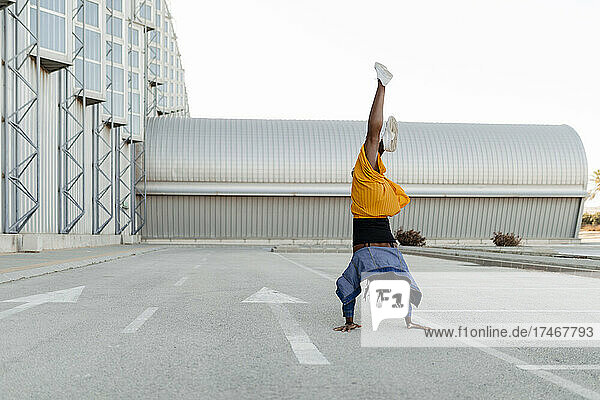 Woman practicing handstand on road