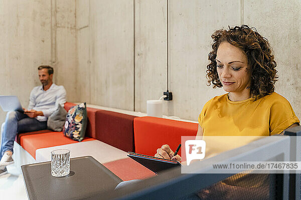 Businesswoman writing in dairy at coworking office