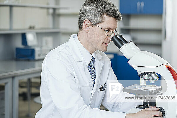 Researcher checking sample through microscope in laboratory