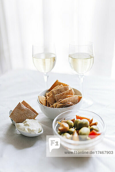 Two glasses of white wine and bowl of crackers with dipping sauce