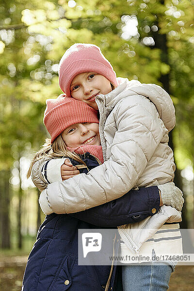 Girls wearing knit hat hugging each other at park