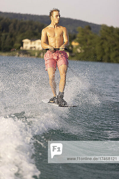 Young man waterskiing on wake in lake