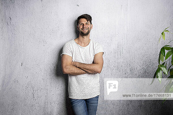 Smiling man with arms crossed in front of white wall