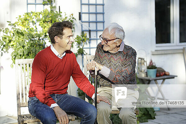 Smiling man talking with father in backyard