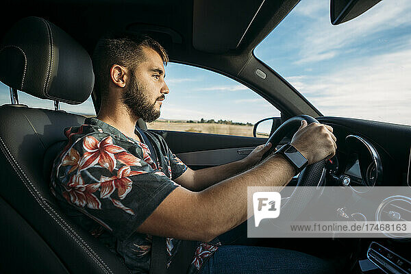 Bearded young man driving car