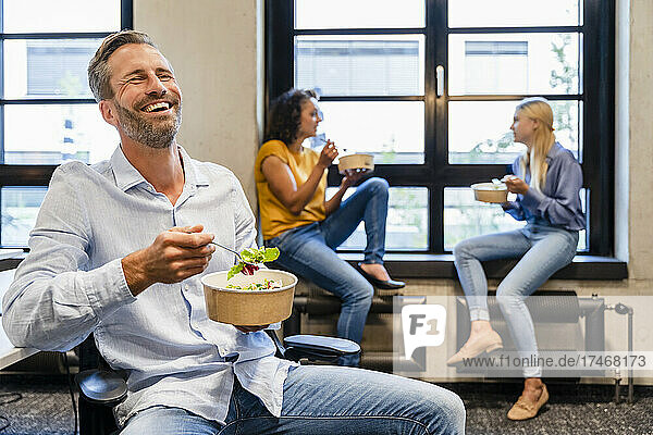 Happy businessman having lunch with colleagues in office