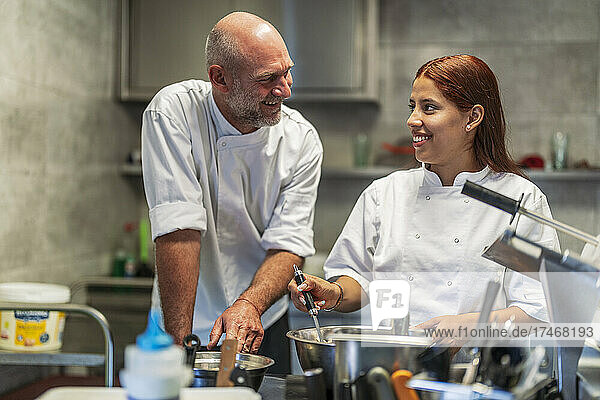 Smiling male and female chefs talking while cooking in kitchen