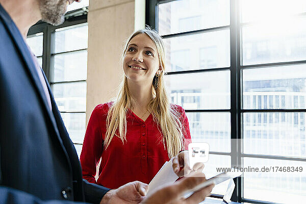 Blond businesswoman discussing with coworker in office