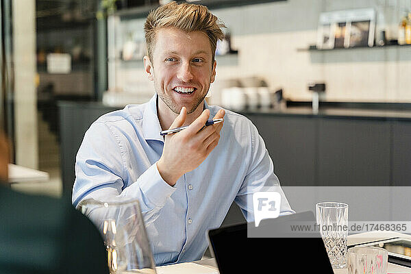 Smiling young businessman discussing with colleague in office