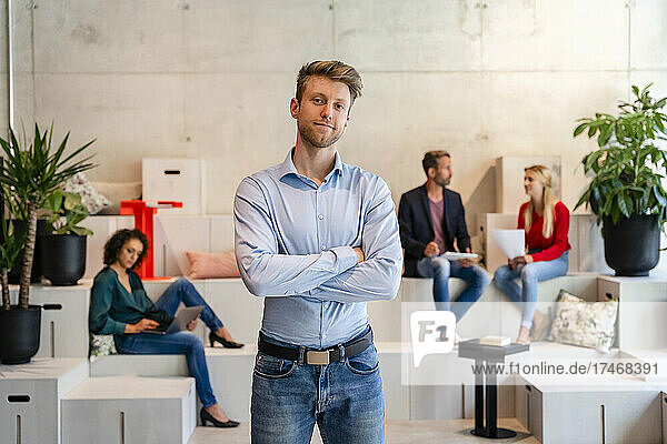 Young businessman with arms crossed in coworking office