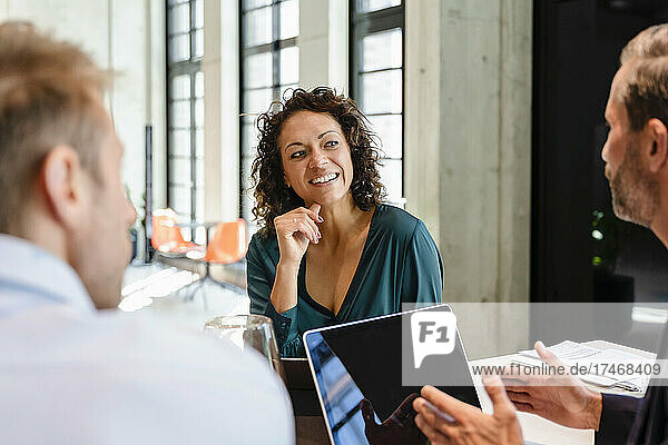 Smiling businesswoman listening to coworker in meeting
