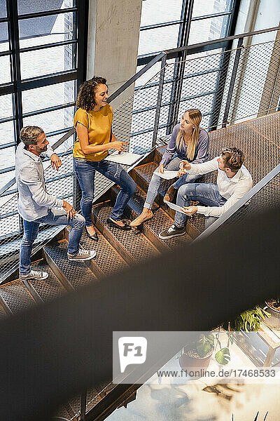 Businesswoman discussing with coworkers on steps in office