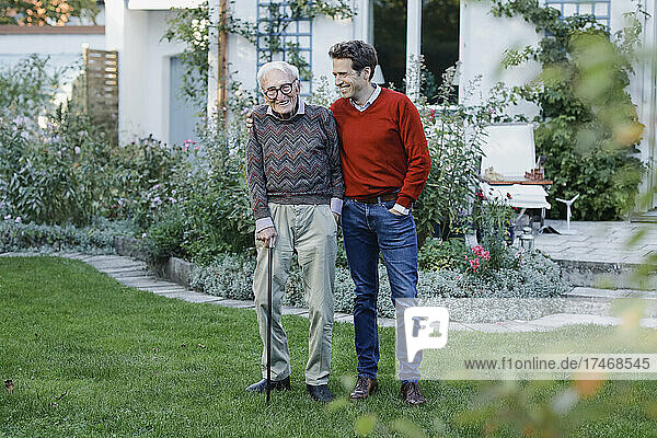 Happy senior man with son on grass in backyard