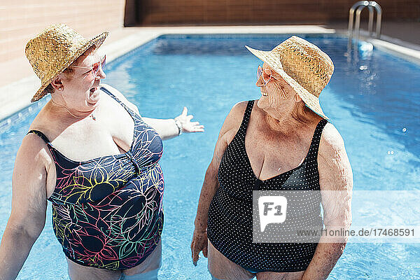 Senior women laughing in pool during sunny day