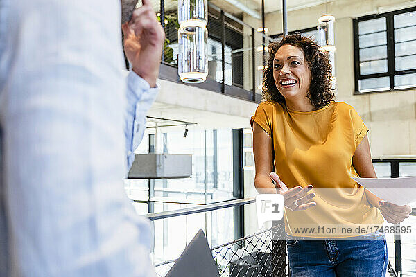 Smiling businesswoman discussing with colleague in office