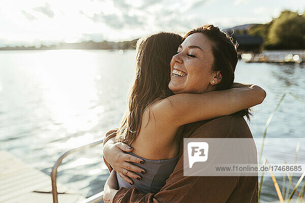 Happy woman hugging yoga instructor by lake