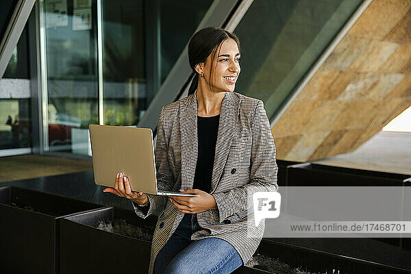 Smiling businesswoman with laptop on bench