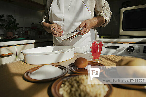 Frau mit Zutaten bereitet Panellets in der Küche zu