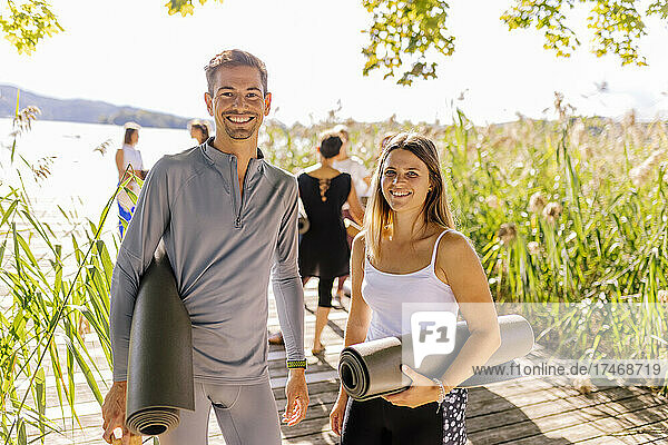 Man and woman standing with exercise mats at yoga class