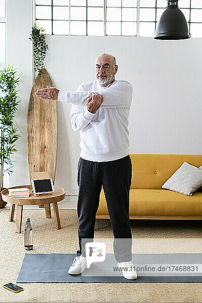 Senior man doing exercise on mat at home