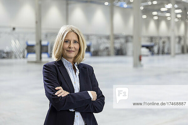 Confident businesswoman standing with arms crossed in industry