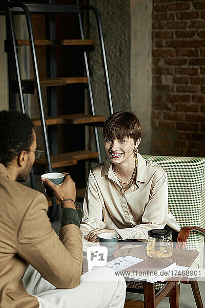 Happy teenage girl talking with boyfriend having tea in cafe